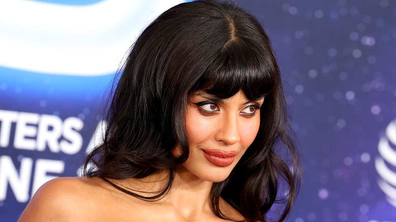 Photo inclinée et rapprochée de Jameela Jamil sur le tapis rouge, avec des yeux enfumés et un rouge à lèvres nu