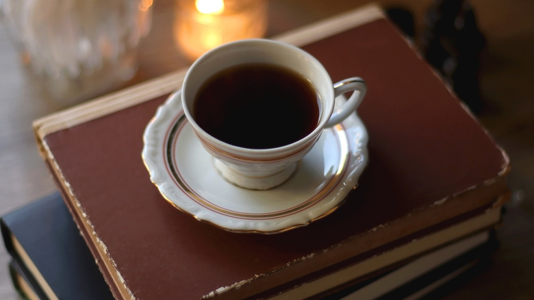Une tasse de thé assis sur une pile de vieux livres