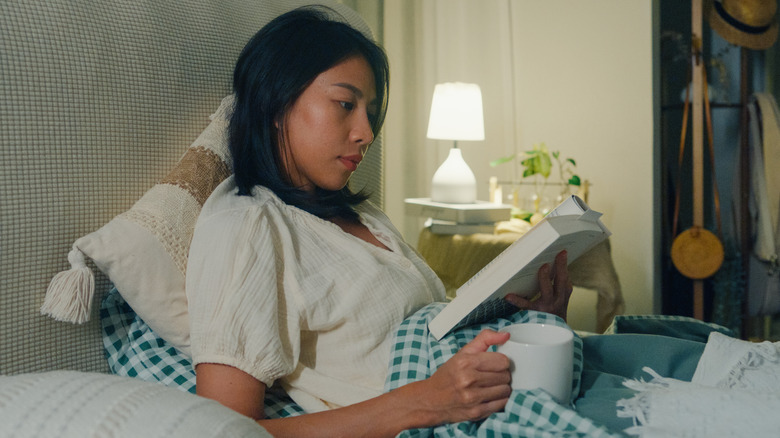 Une jeune femme au lit avec un livre