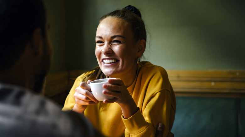 Une femme tenant une tasse de thé et riant