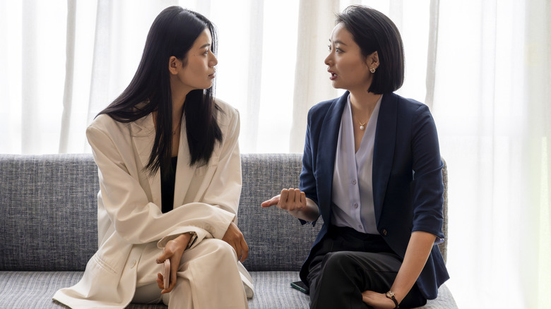 Deux femmes en costume assises sur un canapé et parlant