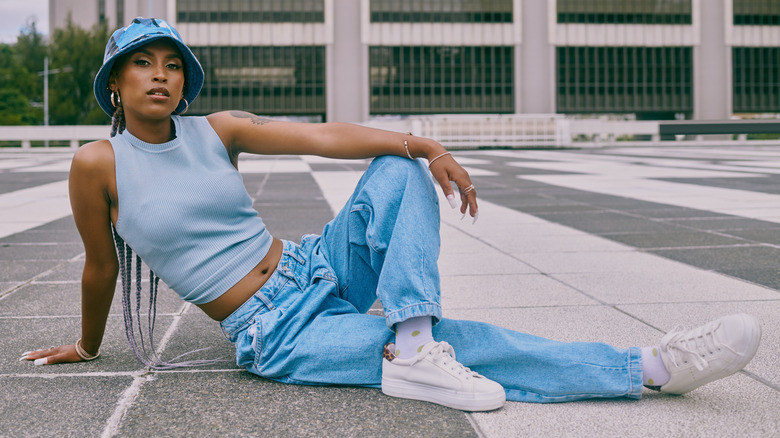 Femme assise sur le sol avec un jean baggy