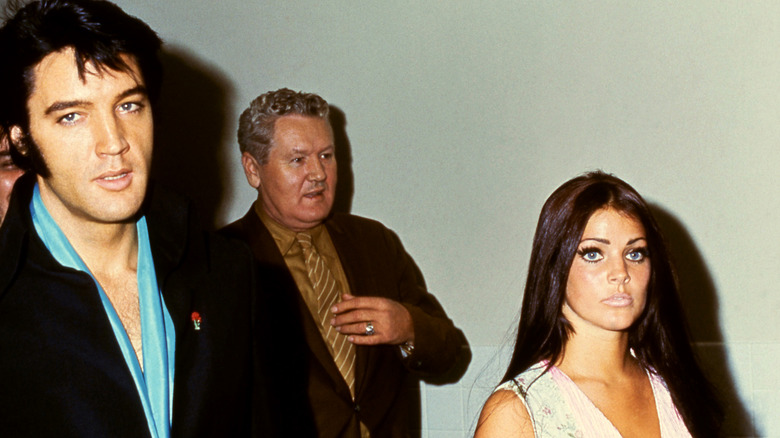 La chanteuse américaine Elvis Presley (1935 - 1977) marche avec son épouse, l'actrice Priscilla Presley et le père Vernon Presley vers 1970