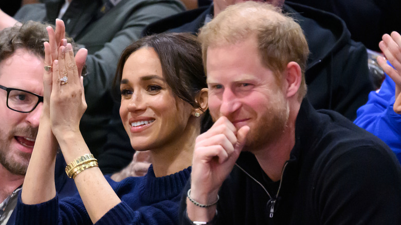 Meghan Markle et le prince Harry se sont assis à un jeu de sport et souriant