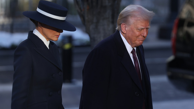 Melania Trump dans un chapeau bleu et blanc avec Donald Trump dans une veste noire
