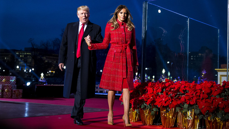 Donald Trump tient la main de Melania Trump alors qu'elle porte un manteau rouge