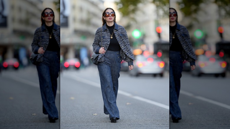 Une femme marchant dans la rue dans une veste en tweed bleue sur un col roulé noir et un jean bleu