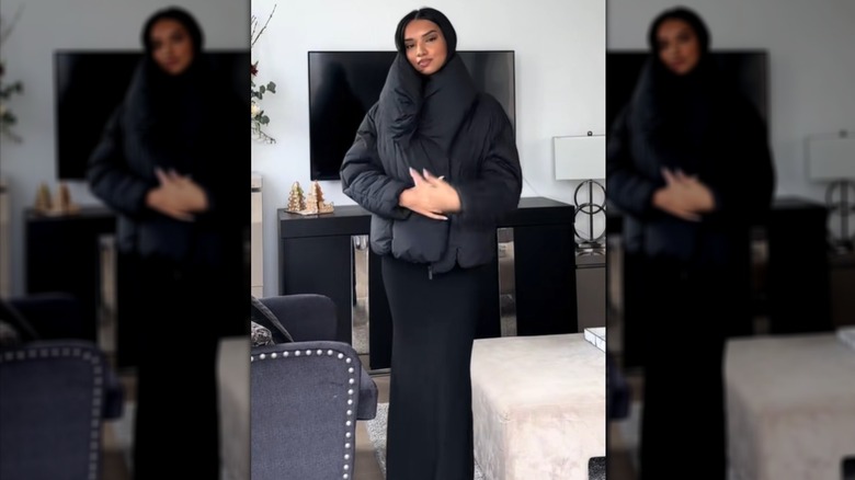 Une femme vêtue d'une doudoune noire avec une robe en satin noir