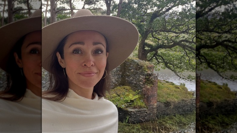 Autumn Reeser posant dans un cadre naturel devant une vieille structure en brique