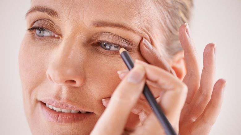 Une femme mûre s'applique un eye-liner