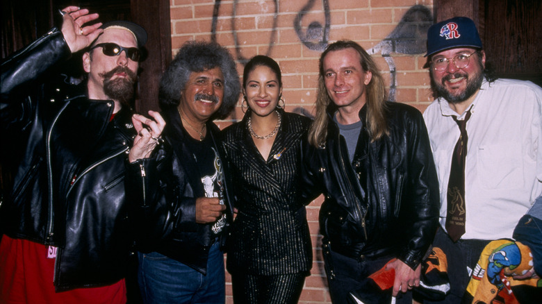 Selena posant avec un groupe d'hommes au Hard Rock Café tout en portant un costume rayé scintillant