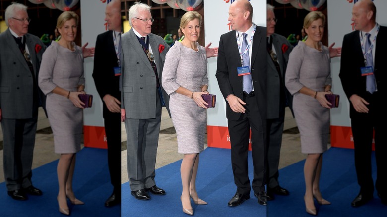 Sophie, duchesse d'Édimbourg, entourée d'hommes en costume et portant une robe ajustée à motifs