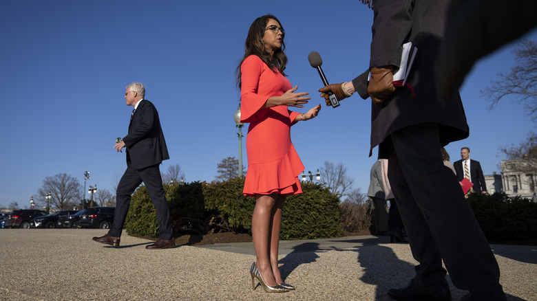 Lauren Boebert portant une robe orange et s'adressant aux journalistes