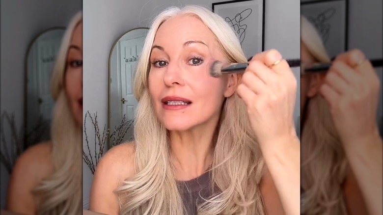 Une femme plus âgée appliquant du blush