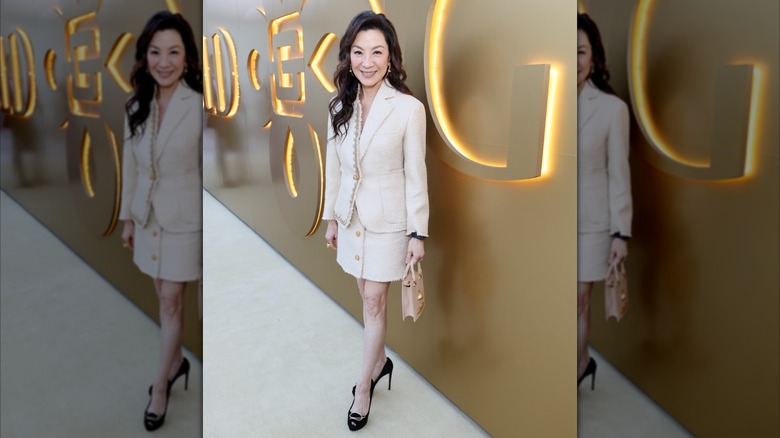 Michelle Yeoh souriante lors d'un événement Gold House tout en portant une mini-jupe et un blazer assortis