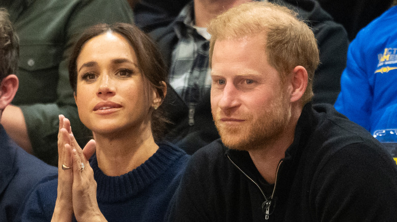 Meghan Markle et le prince Harry assis dans une foule
