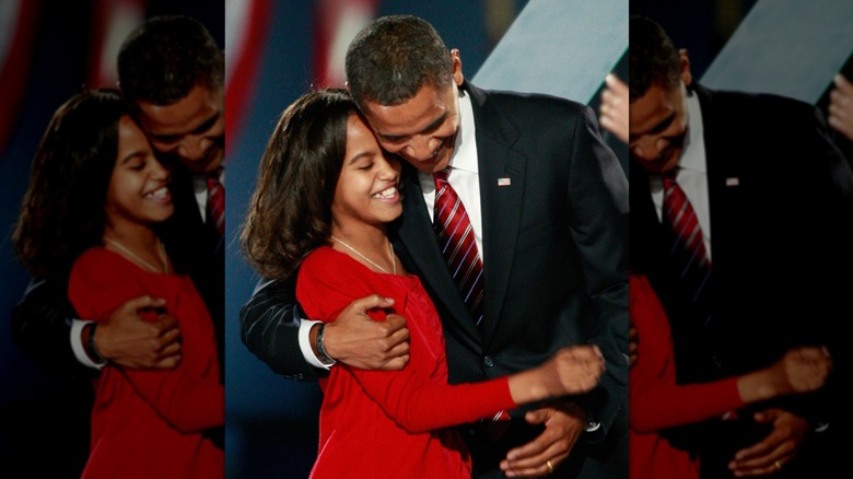 Malia Obama, aux cheveux légèrement bouclés, souriante et embrassant son père le soir des élections
