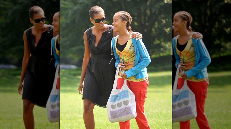 Malia Obama, coiffée en cornrows, souriante en marchant avec sa mère en 2009