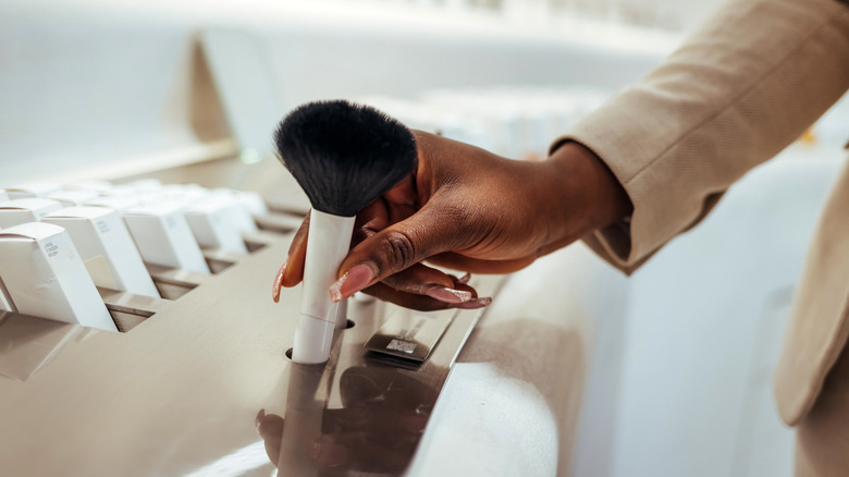 Femme atteignant le pinceau de maquillage