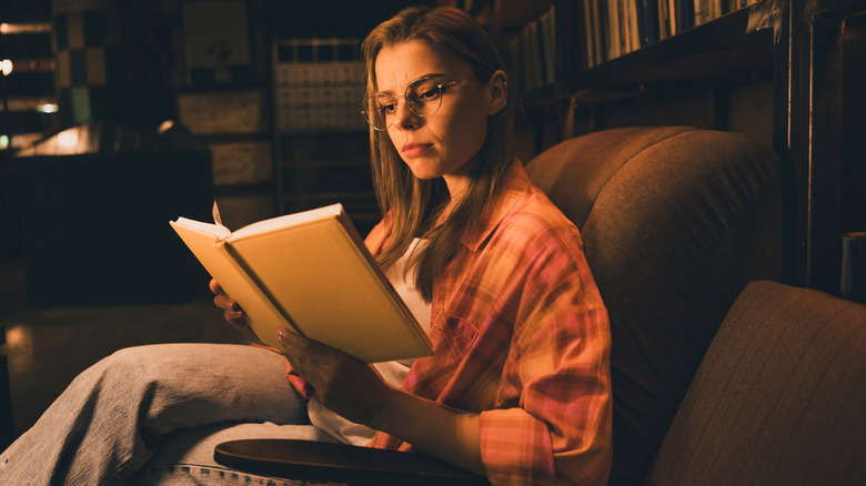 Une pile de livres vintage à côté d’une délicate tasse de thé et de bougies allumées