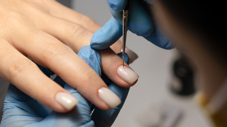 Main avec des ongles nus se faisant une manucure