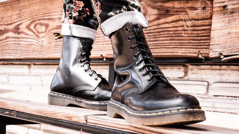 Personne en bottes de combat debout sur une planche de bois