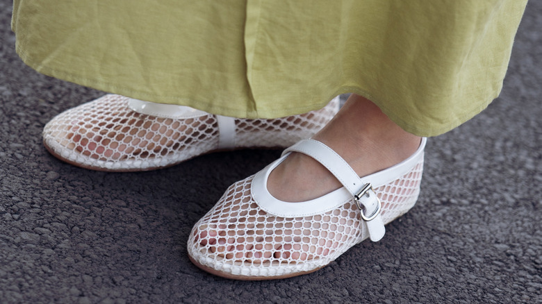 Gros plan d'une femme portant une jupe verte et des chaussures plates en maille blanche avec des bretelles Mary Jane