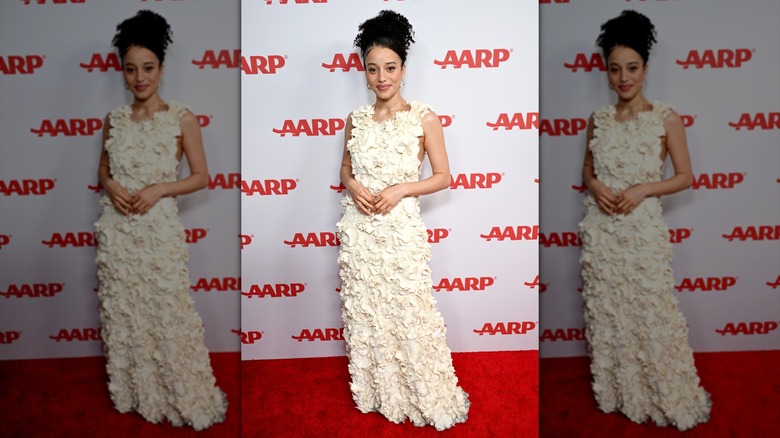 Chase Infiniti souriant aux Annual Movies for Grownups Awards tout en portant une robe longue ornée d'appliques blanches