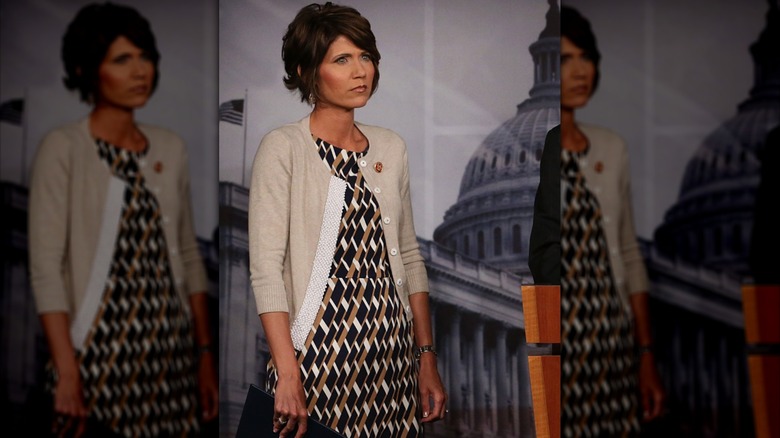 Kristi Noem, en cardigan court beige et robe à motifs géométriques, lors d'une conférence de presse à Capitol Hill en 2013