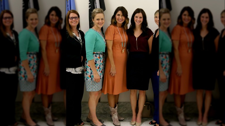Kristi Noem, en robe à manches courtes mandarine, entourée de médecins et d'étudiants de l'American Optometric Association, à Capitol Hill en 2017