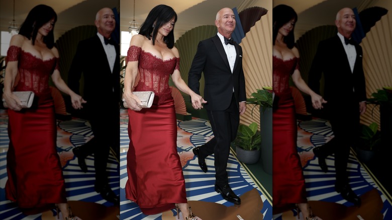 Jeff Bezos marche main dans la main avec Lauren Sánchez Bezos qui porte une robe rouge avec un corsage corset en dentelle