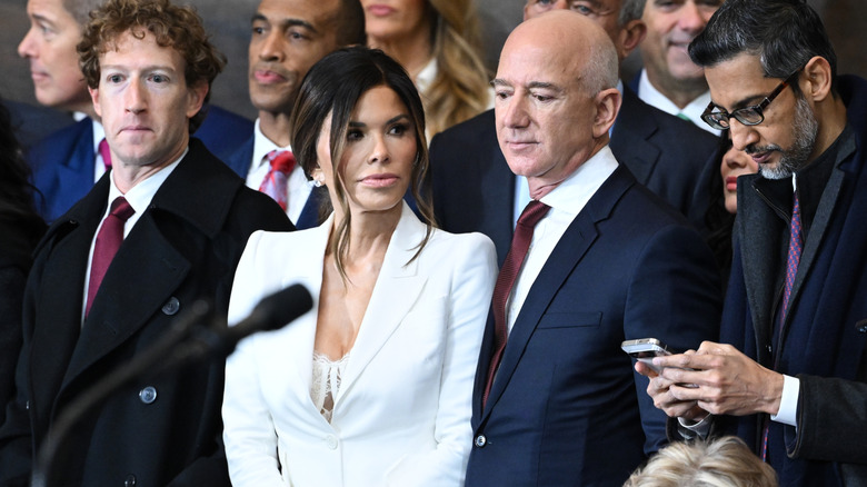 Lauren Sánchez Bezos porte un costume blanc décolleté, flanquée de Mark Zuckerberg et Jeff Bezos
