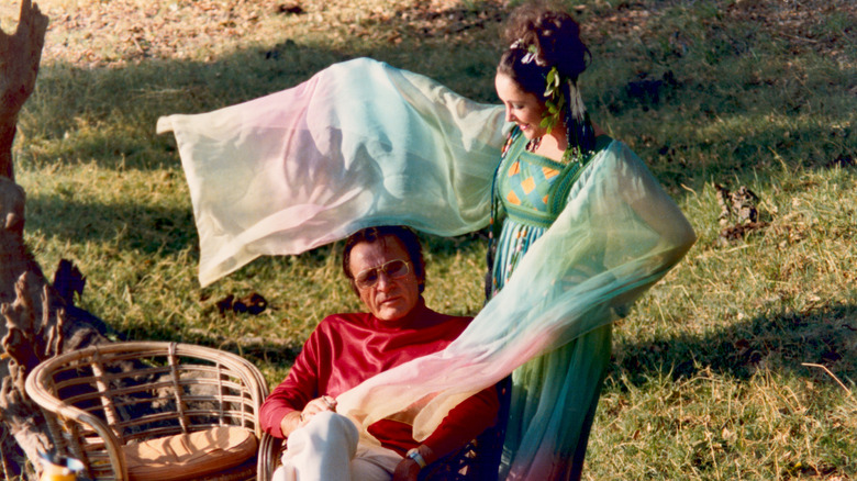 Elizabeth Taylor agitant les manches fluides de sa robe tie-dye autour de son mari Richard Burton