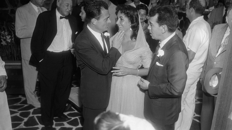 Mike Todd regarde le visage d'Elizabeth Taylor alors qu'elle porte une robe à capuche avec des fronces sur le corsage