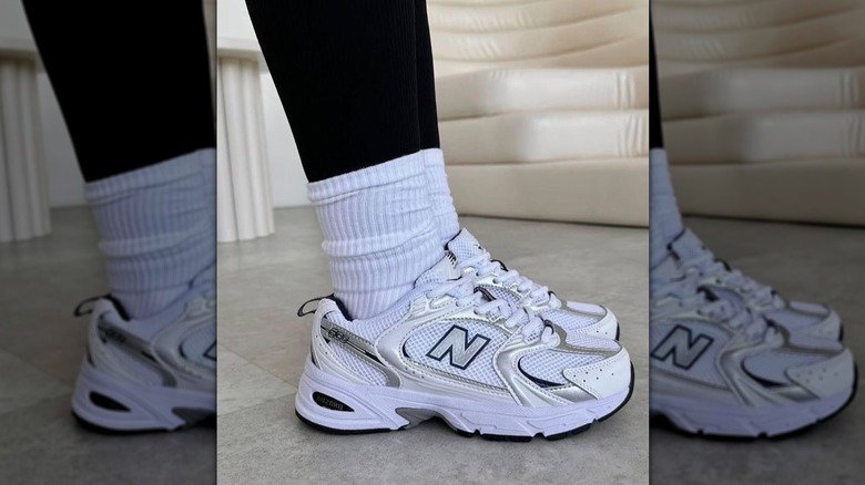 Une femme portant des baskets blanches avec des chaussettes blanches sur des leggings noirs