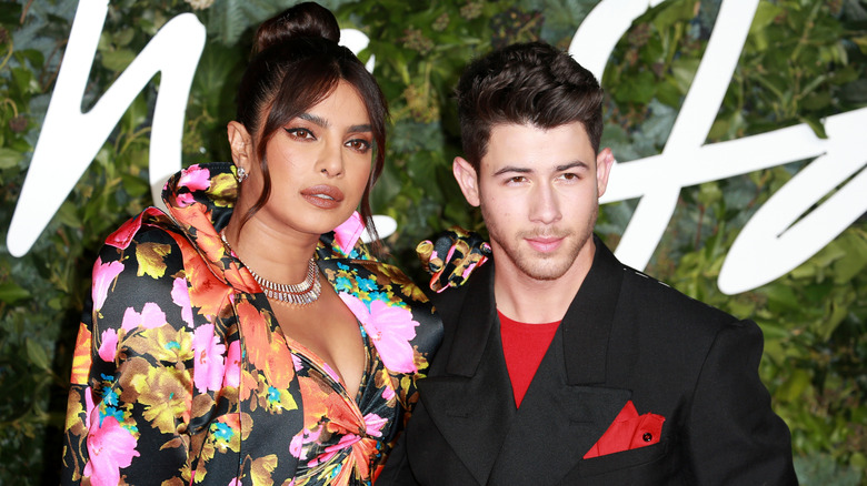 Priyanka Chopra, en robe à fleurs, et Nick Jonas, en blazer noir et chemise rouge, aux Fashion Awards 2021 à Londres
