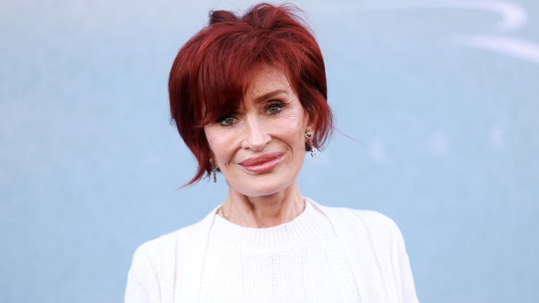 Sharon Osbourne sourit en portant un haut blanc
