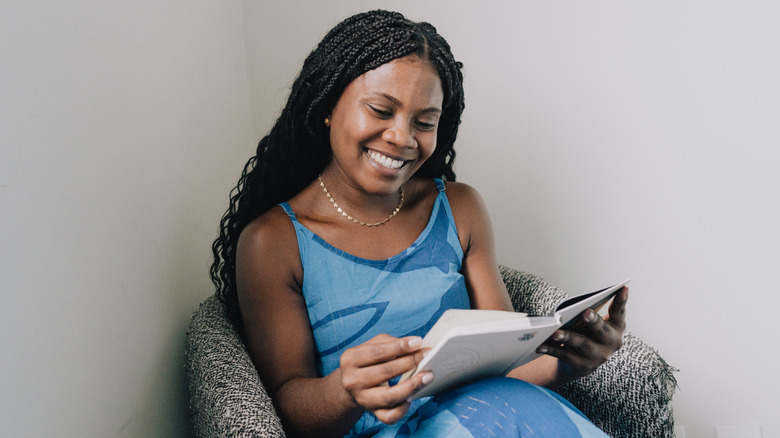 Une femme est assise dans un fauteuil et lit un livre