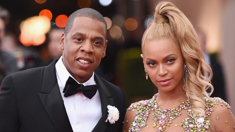 Jay-Z se penche pour une photo avec Beyoncé sur le tapis rouge