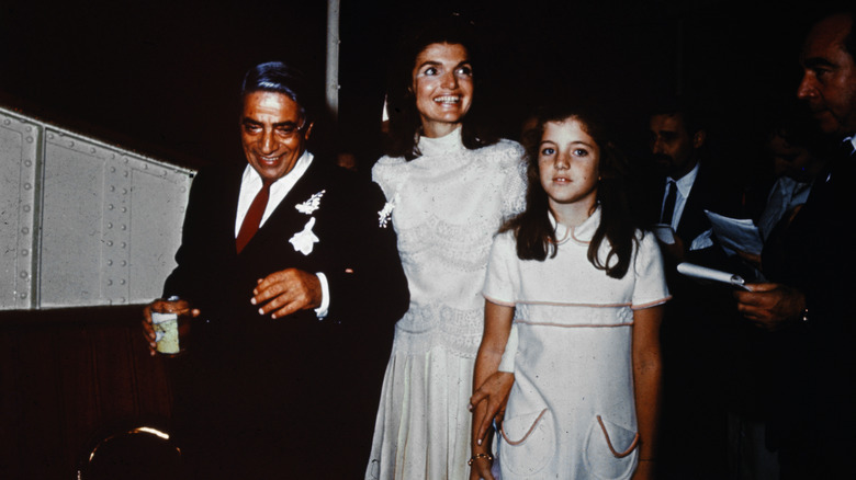 Jacqui Kennedy dans une robe droite blanche à côté d'une jeune Caroline Kennedy et Aristote Onassis