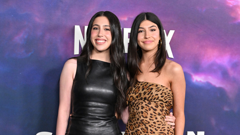 Sadie Sandler souriante dans une robe en cuir noir, à côté de Sunny Sandler souriante vêtue d'une robe à imprimé léopard