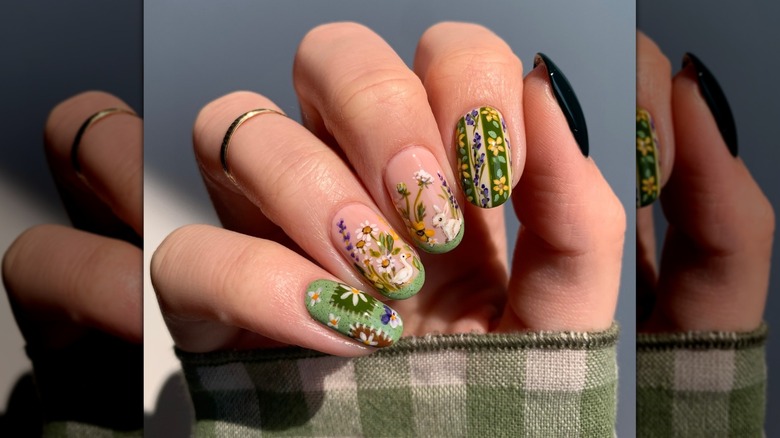Main pliante montrant des ongles avec une variété de motifs verts, jaunes et marron
