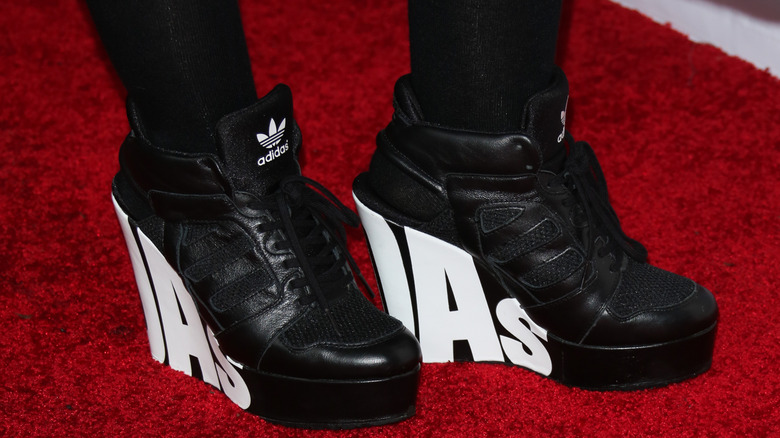 Une femme portant des baskets Adidas compensées sur un tapis rouge