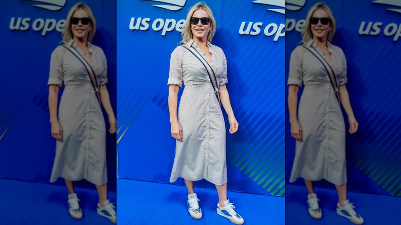 Chelsea Handler dans une robe chemise longue avec des baskets métallisées, posant sur le tapis bleu