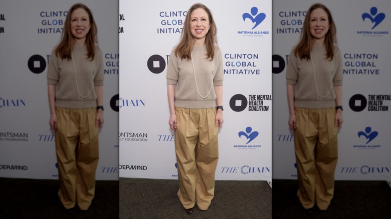 Chelsea Clinton souriante lors d'un événement avec un pull beige