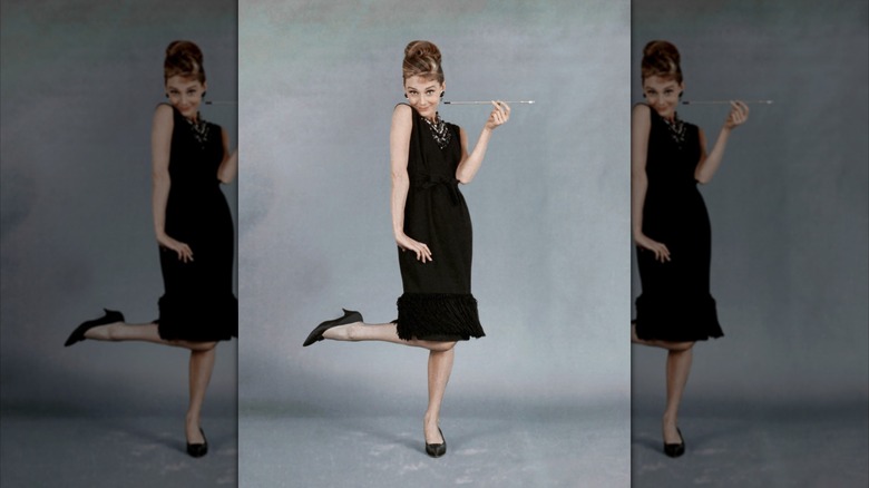 Audrey Hepburn posant pour une photo promotionnelle pour Breakfast at Tiffany's, vêtue d'une robe noire jusqu'aux genoux et de talons noirs