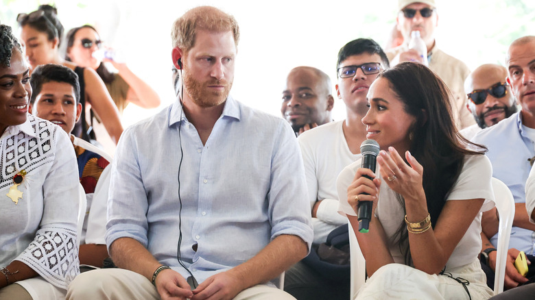 Le prince Harry et Meghan Markle lors d'un événement avec elle tenant un micro