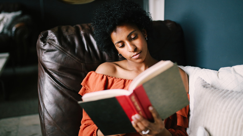 Jeune femme se reposant sur le lit en lisant un livre