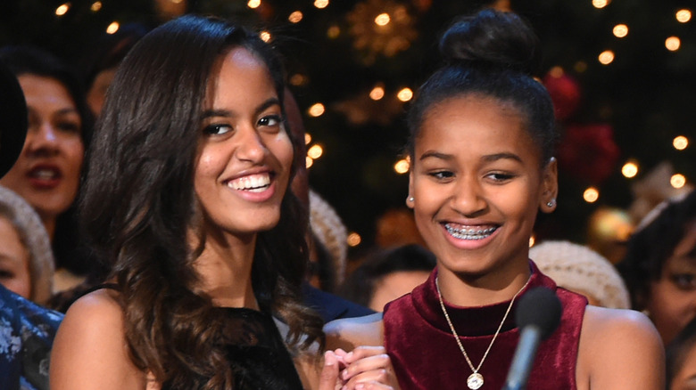 Malia Obama sourit à côté de Sasha Obama derrière un micro