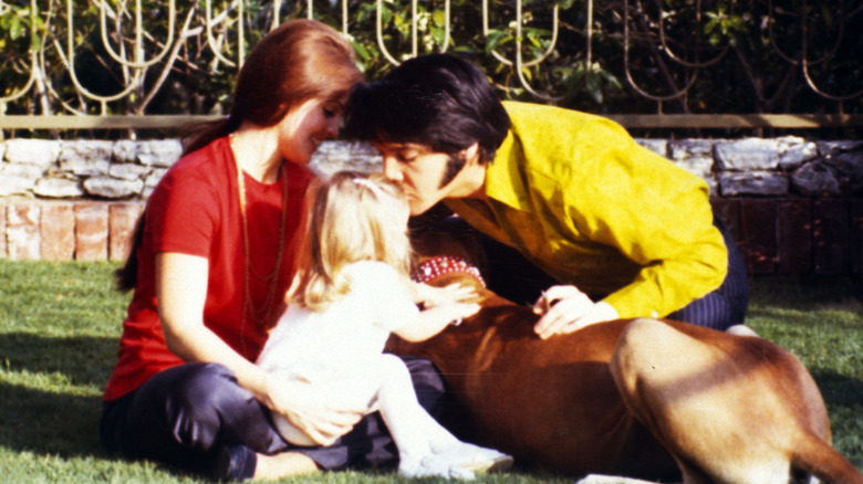 Elvis Presley embrasse Lisa Marie Presley sur la tête alors qu'elle est assise sur Priscilla Presley